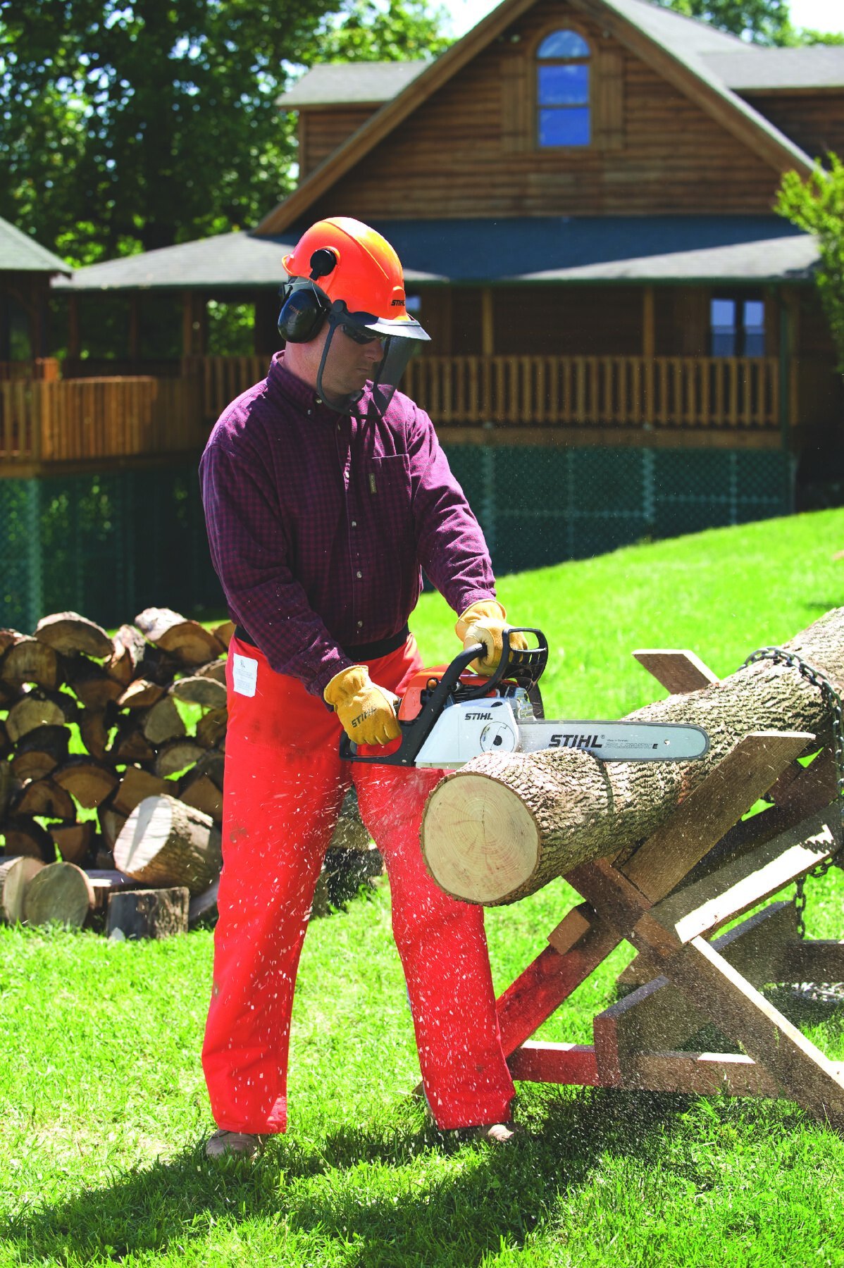 STIHL equipment operator in protective helmet and gear holding a STIHL chainsaw